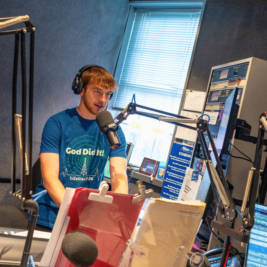 "Young man recording in a radio studio with professional equipment and soundproof walls.".