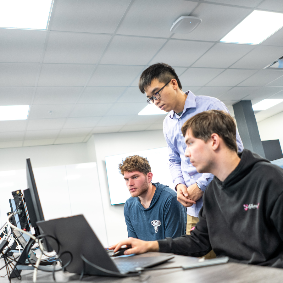 Young men collaborating on computer programming project in a tech office.