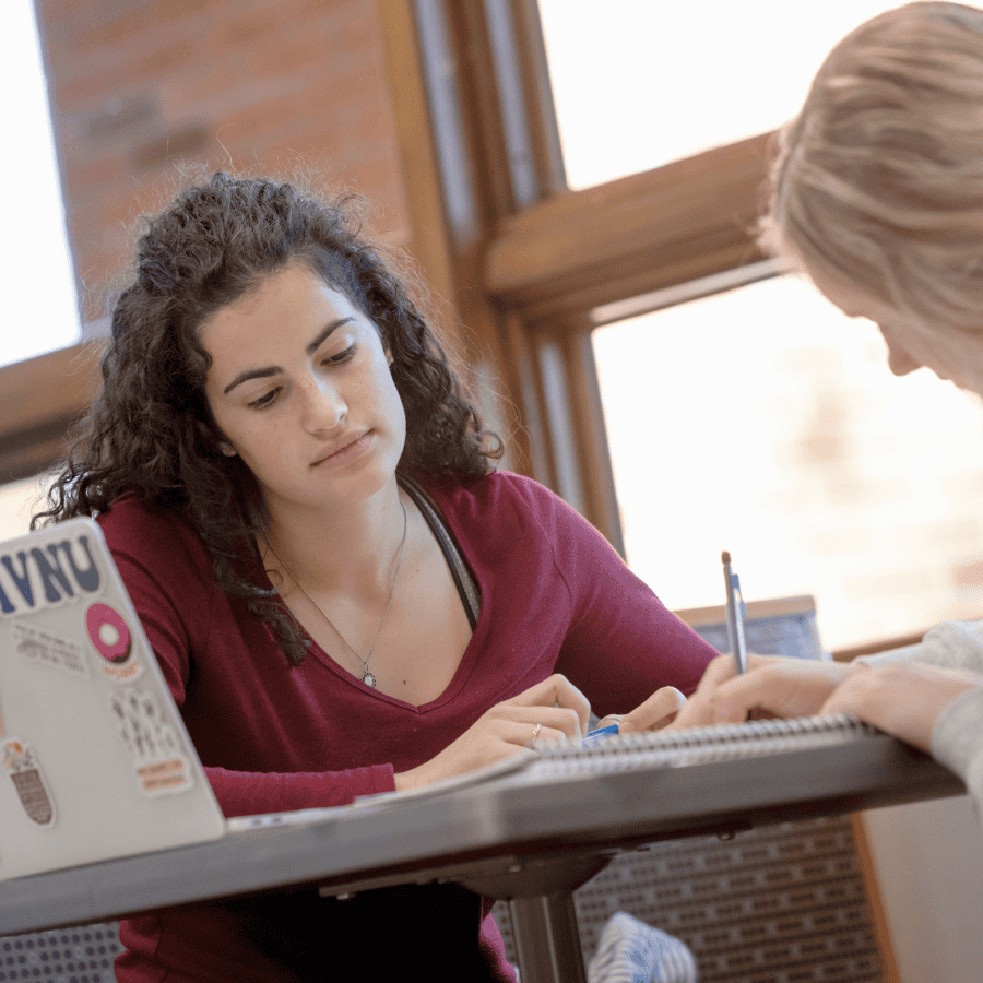 Studying together at a table in a bright room with large windows.