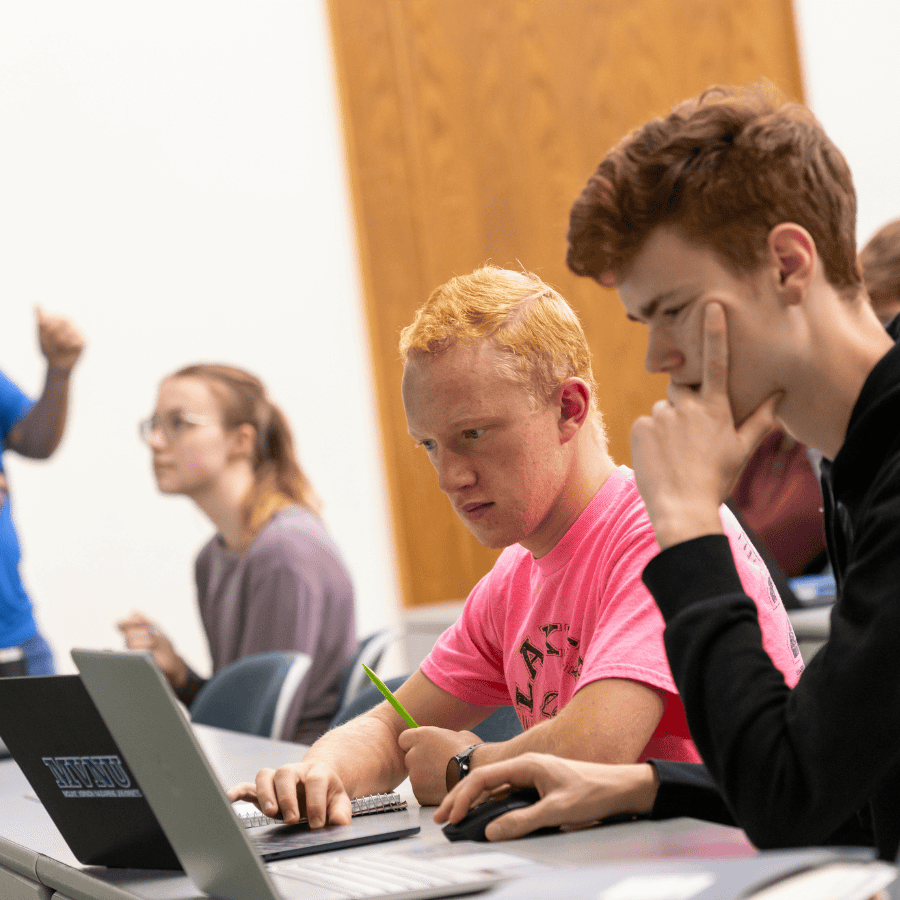 Students attentively listening and taking notes during a classroom lecture with a teacher in the bac.