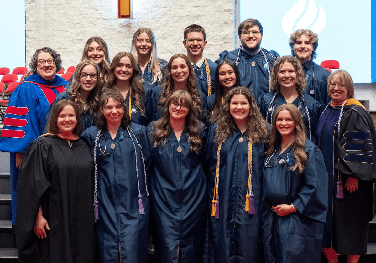 Group of nursing graduates in caps and gowns at ceremony.