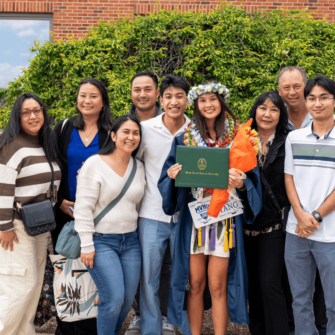 Group of diverse graduates and family celebrating graduation outdoors.