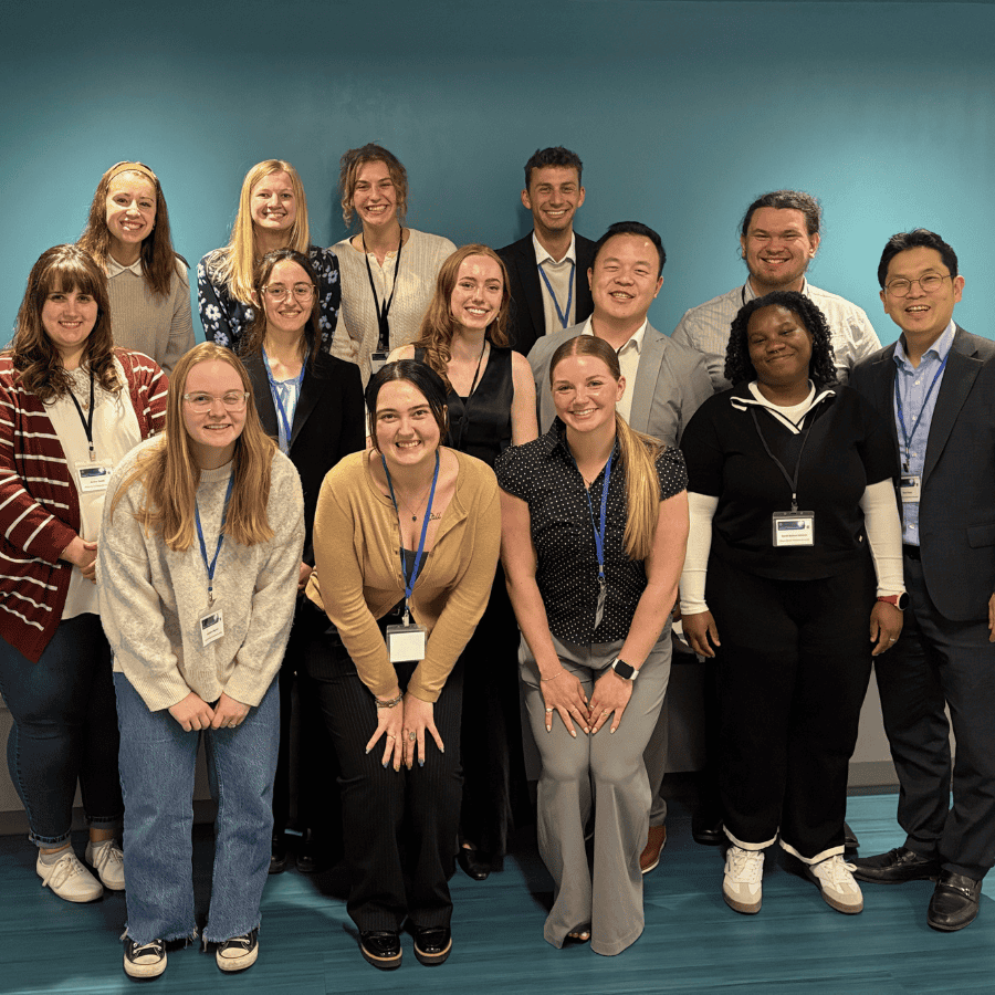 Diverse group of young adults smiling at a conference or workshop in a classroom setting.