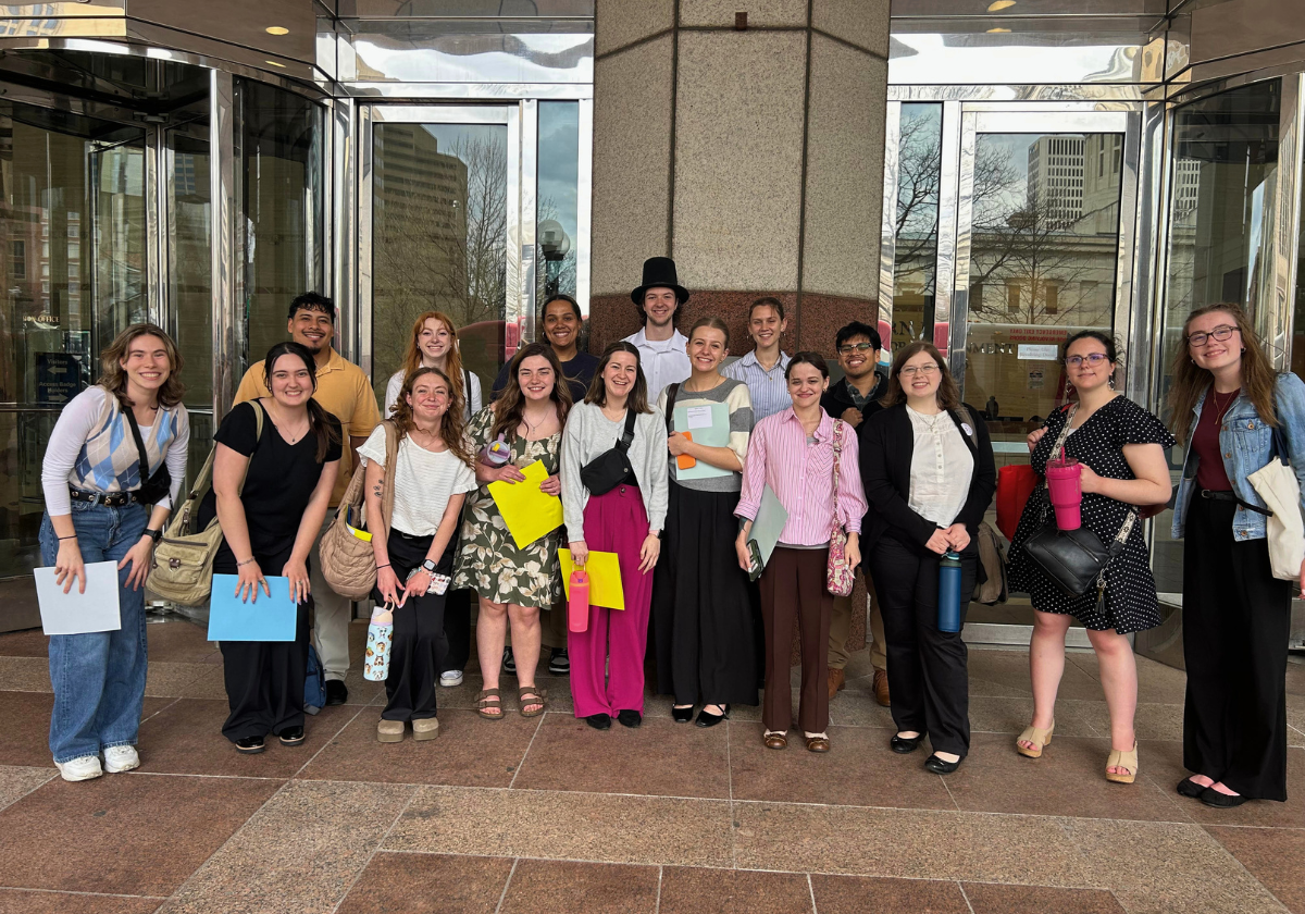 A vibrant group of diverse young adults standing outside a modern building entrance.