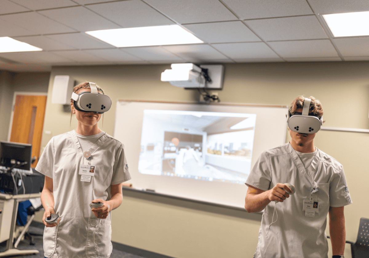 AR headset users practicing in a training room with a projected medical image on the screen behind t.