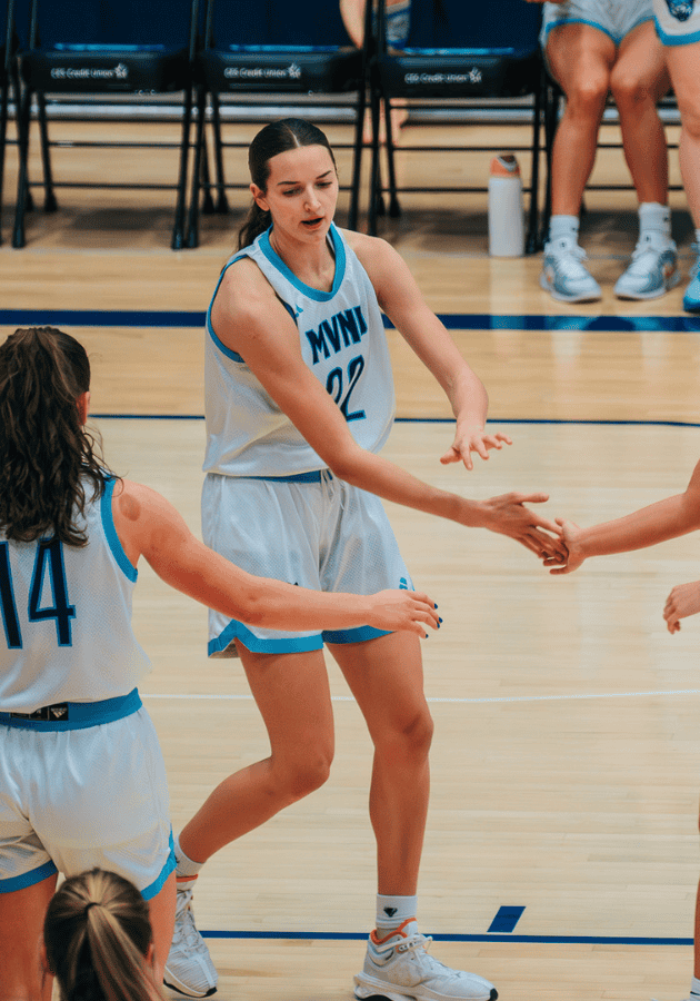 Female basketball players exchanging a handshake on the court after a game or practice.